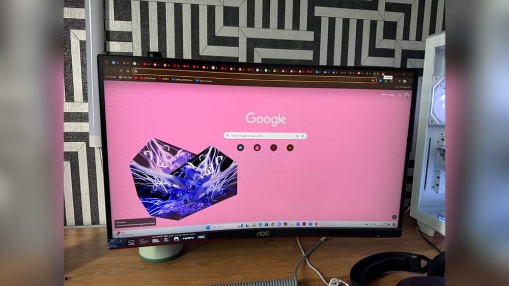AOC monitor displaying Google Chrome browser with custom wallpaper, part of a gaming setup.