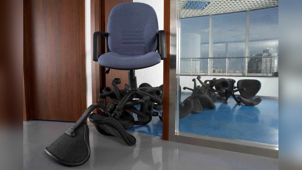 Office chair chaos: a pile of overturned chairs by a doorway, reflecting a messy workspace.