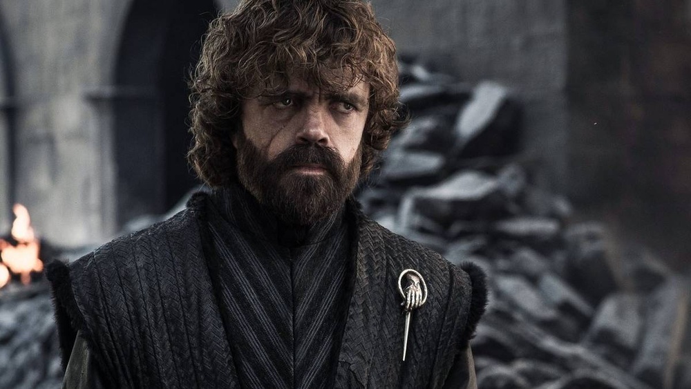 Tyrion Lannister from Game of Thrones, wearing a Hand of the King pin, looking stern.